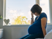 A pregnancy woman holds her head.