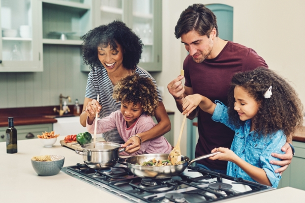 Shot of a family of four cooking together in their kitchen at home