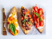 Directly above close up shot of bruschettas with tomato, basil, capers, bell pepper and cheese