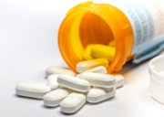 Close-up of pills spilling from bottle on white background