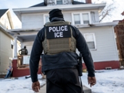 A federal law enforcement agent outside a home during a raid in south Minneapolis, Minnesota, US, on Tuesday, Jan. 13, 2026. Minnesota officials are suing over the unprecedented surge of US immigration authorities in the state, taking the Trump administration to court days after a federal agent shot and killed a Minneapolis woman. Photographer: Victor J. Blue/Bloomberg via Getty Images