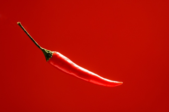 A red chili pepper floating on the center of an red background