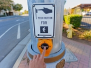 Perris, California - December 6, 2025: Hand pressing yellow pedestrian crossing button on a light pole in Perris, California, promoting safety and accessibility for city walkers.