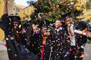Group of cheerful black students celebrating graduation day at the university campus