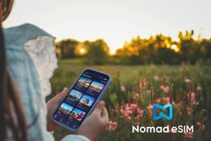 A woman usuing a phone with a field in the background