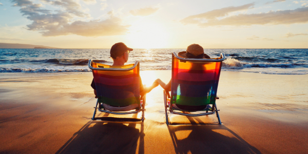 A couple sitting in beach chairs watching the sunset