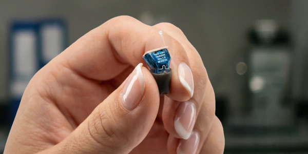 A hand holding a hearing device