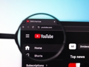 The YouTube logo is displayed through a magnifying glass in this photo illustration in Ontario, Canada, on February 9, 2026. (Photo by Thomas Fuller/NurPhoto via Getty Images)