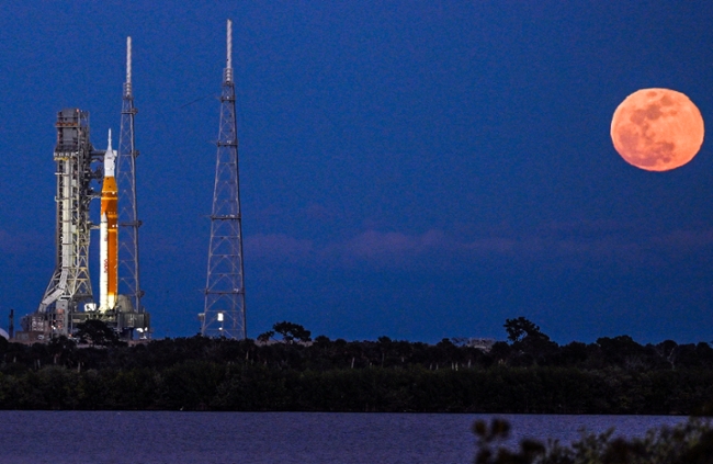 A full moon rises as the Space Launch System (SLS) rocket and the Orion spacecraft, integrated for the Artemis II mission, are seen at Launch Pad 39B at the Kennedy Space Center in Cape Canaveral, Florida, on February 1, 2026 ahead of the first crewed mission to the Moon in more than 50 years. (Photo by Miguel J. Rodriguez Carrillo / AFP via Getty Images)