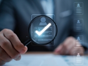 Businessman holding magnifier glass to focus on resume with tick mark for selection person to interview job and human recruitment concept.