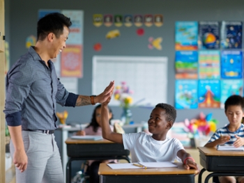 Smiling teacher and diverse students enjoying interaction in a vibrant classroom environment, promoting learning and positivity. Encouragement and support foster collaboration and inspire success among young learners.