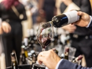 A winemaker pours red wine for guests at a wine tasting