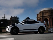 SAN FRANCISCO, CALIFORNIA - DECEMBER 08: A Waymo robotaxi drives by the Palace of Fine Arts on December 08, 2025 in San Francisco, California. Self-driving taxi company Waymo said it is voluntarily recalling software in its autonomous vehicles after Texas officials documented at least 19 incidents this school year in which the cars illegally passed stopped school buses, including while students were getting on or off. (Photo by Justin Sullivan/Getty Images)