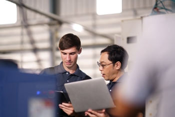 IT support technicians inspecting machine at manufacturing sites