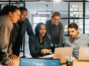 Businesswoman explaining strategies to team over laptop in office meeting room