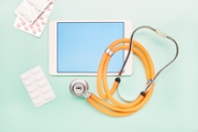 High angle view of tablet computer, stethoscope and pills on turquoise background