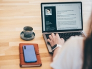 Young business woman searching for job online. Woman writing resume on laptop.