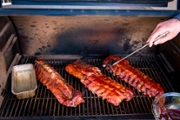 Pitmaster mops baby back ribs with sauce