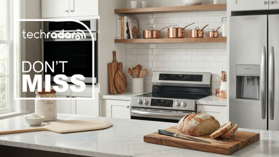 a modern white-themed kitchen with an island, range, built-in oven and larder-style fridge