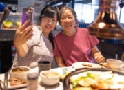 Happy mother and daughter celebrating mothers day and taking selfie at restaurant
