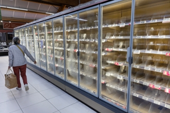 TOPSHOT - A woman walks past empty fresh-food refrigerators at an Intermarch&eacute; supermarket in N&eacute;vez, western France, on October 12, 2026, following a cyberattack affecting the French supermarket chains Intermarch&eacute; and Cooperative U that caused their refrigerators to defrost. Some 150 to 200 Intermarch&eacute; stores were targeted in the attack on October 12, 2026, along with nearly 100 Coop&eacute;rative U outlets, the retailers said. BFM TV reported that rival giant E. Leclerc was also affected, with hackers "managing to remotely trigger the forced defrosting of refrigeration systems in numerous stores." (Photo by Fred TANNEAU / AFP via Getty Images)