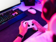 Gamer holding gamepad and playing video game on desktop