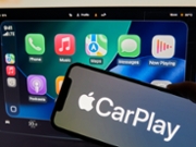 An iPhone showing Apple CarPlay is seen in front of a Tesla Model 3 screen displaying a CarPlay-style interface in Bari, Italy, on November 15, 2025. (Photo by Matteo Della Torre/NurPhoto via Getty Images)