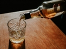A bottle of whisky is poured into a cut glass tumbler over ice. Space for copy.
