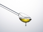 Transparent Glass Spoon Filled With Cooking Oil on White Background Close-up View.