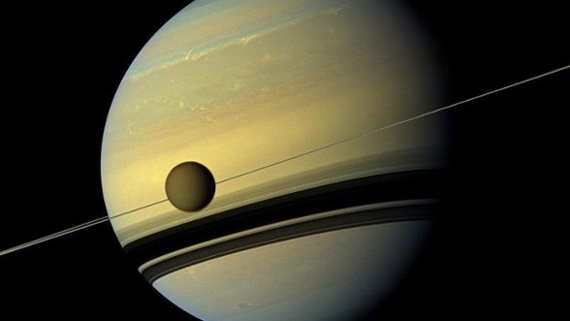 a pale yellow planet surrounded by thin white rings