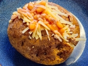Nottingham, England, December 21, 2024. An excellent and hearty, typically English dish. These are jacket potatoes, whole potatoes baked in the oven with the peel and then stuffed. In the photo, the potato is cut in half and topped with tuna, beans, and thinly sliced ​​cheddar cheese.