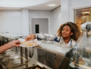 A happy, smiling woman serves teenage pupils their choice of lunch in a school cafeteria.