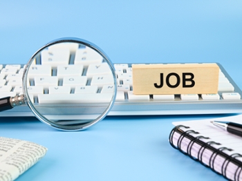 Concept of job search. Magnifying glass and keyboard on blue background.