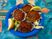 A plate of baked stuffed clams, also known as stuffies, is garnished with fresh lemon wedges and served on a bed of lettuce. This classic seafood appetizer is a New England favorite.