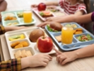 Little kids eating lunch at wooden table in school canteen, closeup