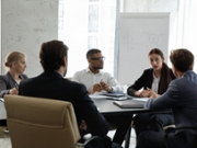 Diverse young and middle-aged partners engaged in group meeting, gathered in board room listen to team leader share ideas, offer solutions looks serious and confident. Business workshop event concept