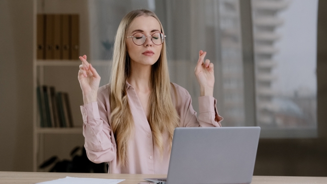 A woman crossing her fingers in front of a laptop