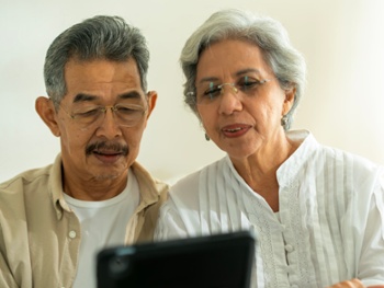 Close-up shot of senior Southeast Asian Couple Learning to use digital tablet while living independently in cozy room.