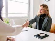 Smiling HR manager shaking hands with candidate at desk