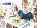 Smiling girl holding food tray in school cafeteria