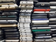 Background of damaged mobile phones. A bunch of broken smartphones. Used phones stacked on top of each other. Repair services and maintenance of equipment.