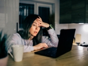 Tired and upset midl-aged woman works in a home office at night