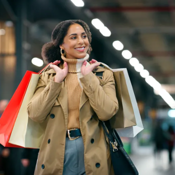 A happy woman carrying shopping bags over her shoulder.