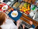 A high angle view of a young teenage girl who is looking at the options for her lunch in the school she goes to in the North East of England. There is plenty of choice of fresh fruit and snacks to choose from in the chiller cabinet.