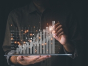 Businessmen are using tablet computers to analyze trends of fast-growing businesses with rising graph bars on a black background.