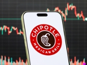 CHONGQING, CHINA - JANUARY 29: In this photo illustration, a smartphone displays the logo of Chipotle Mexican Grill, Inc. (NYSE: CMG), an American fast-casual restaurant chain specializing in Mexican-inspired food including burritos, bowls and tacos, in front of a screen showing the company's latest stock market chart on January 29, 2026 in Chongqing, China. (Photo illustration by Cheng Xin/Getty Images)