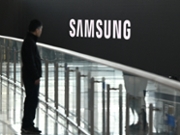 A man stands in front of a large electronic screen showing the Samsung logo at a train station in Seoul on April 30, 2026. South Korean tech giant Samsung Electronics posted a record quarterly profit on April 30, driven by strong sales of chips crucial for artificial intelligence. (Photo by Jung Yeon-je / AFP via Getty Images)