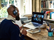 Mid adult man at desk with computer during business team meeting with colleagues, teamwork, communication, remote working