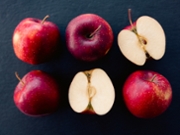 Whole and halved red apples on dark background