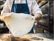 Shot of pizza master kneading pizza dough in professional kitchen.